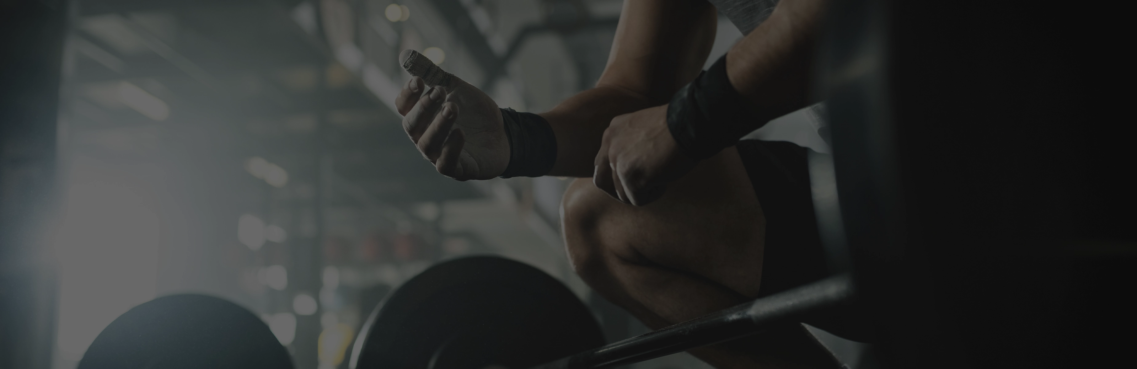 Atleta preparando as mãos para o treino junto à barra e às anilhas